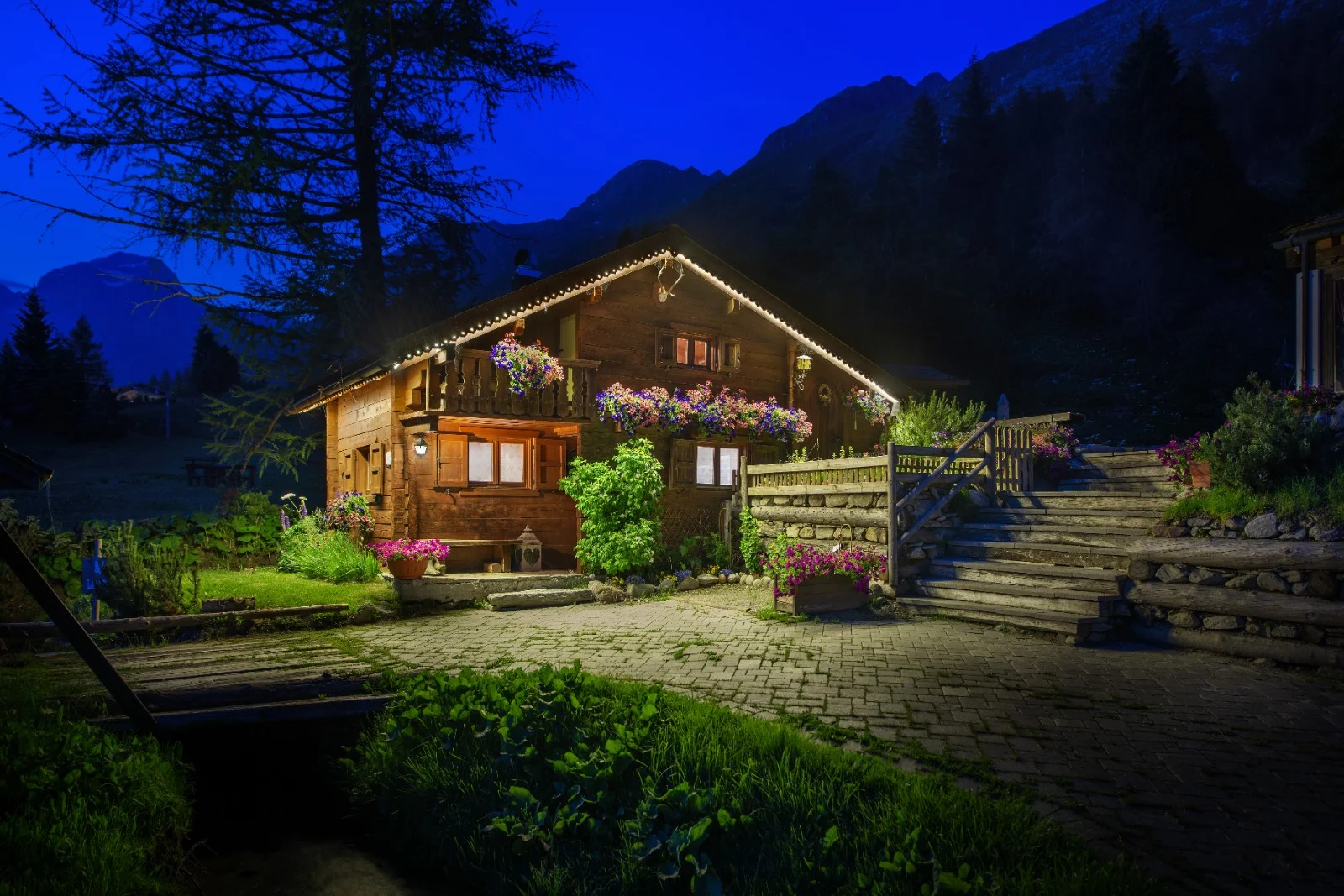 La baita illuminata nell'ora blu, con le montagne della Valle Spluga sullo sfondo
